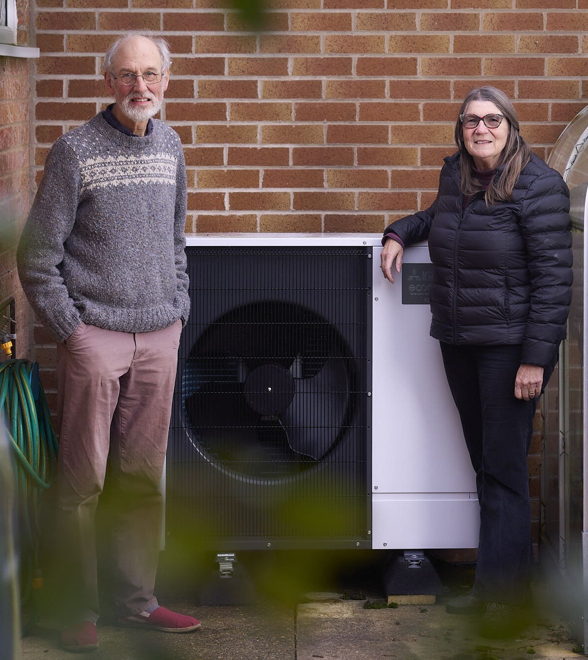 A man and woman standing in front of an Air Source Heat Pump 