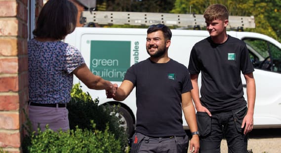 A woman standing in front of a door shaking hands with a Green Building Renewables installer 