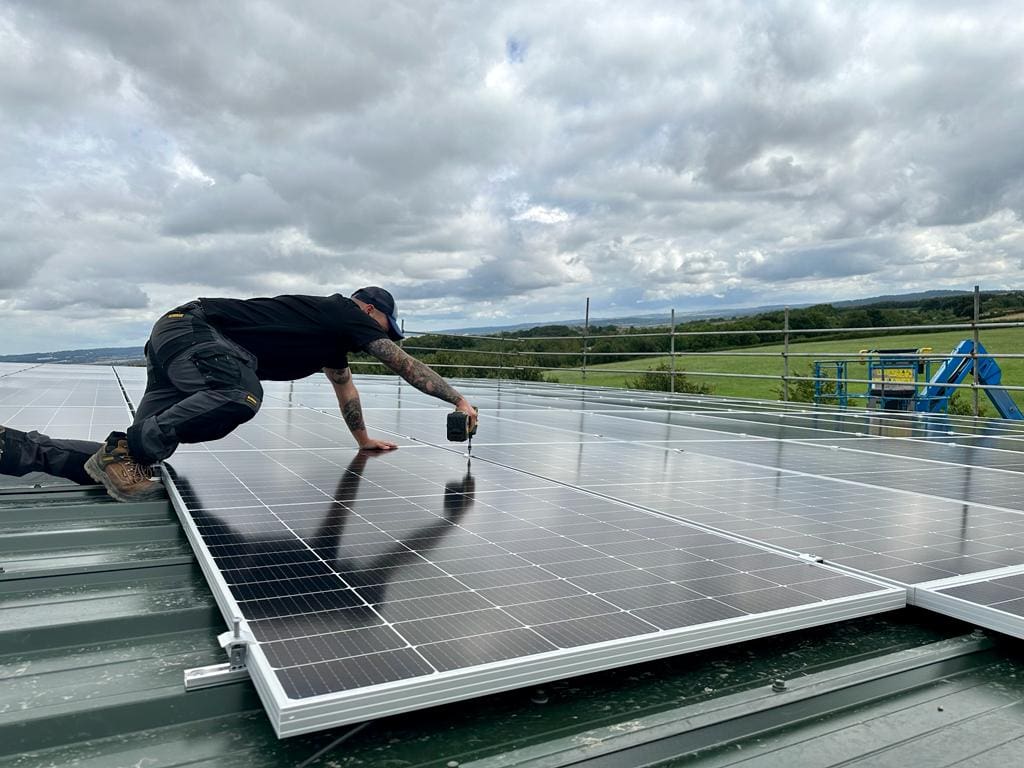 An installer installing a solar panel on a roof